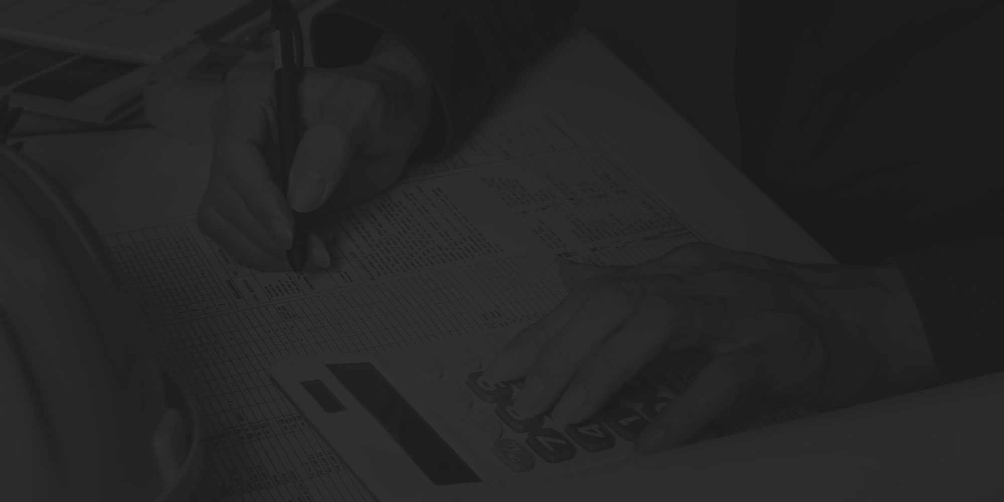 Stack of papers with a person drawing figures and calculations onto a draft.